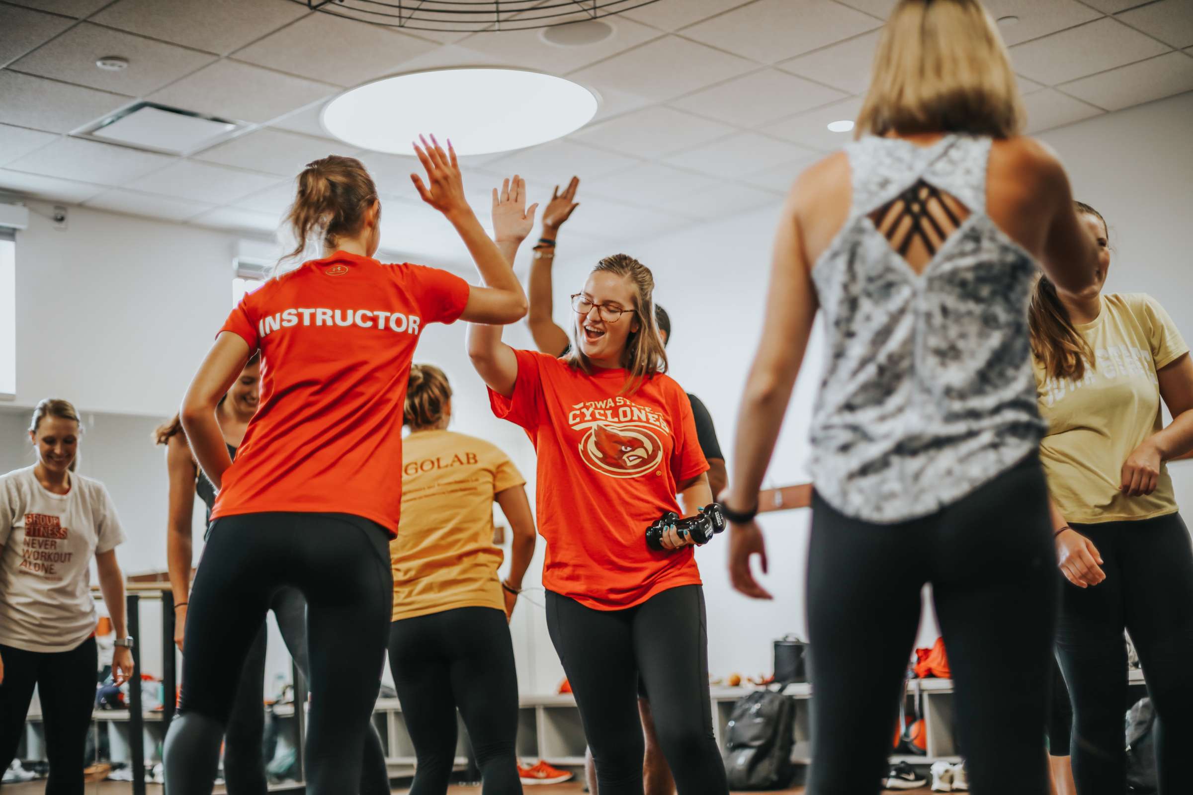 A student and instructor high-five during a group fitness class