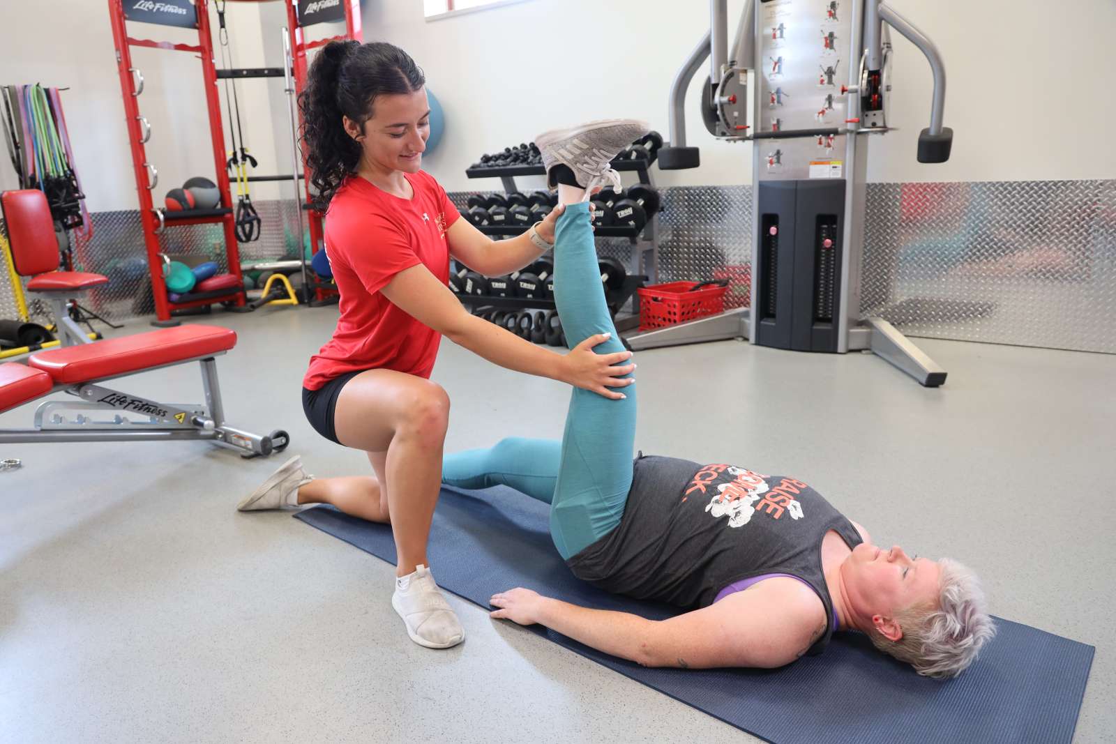 A personal trainer helps a client with a leg stretch