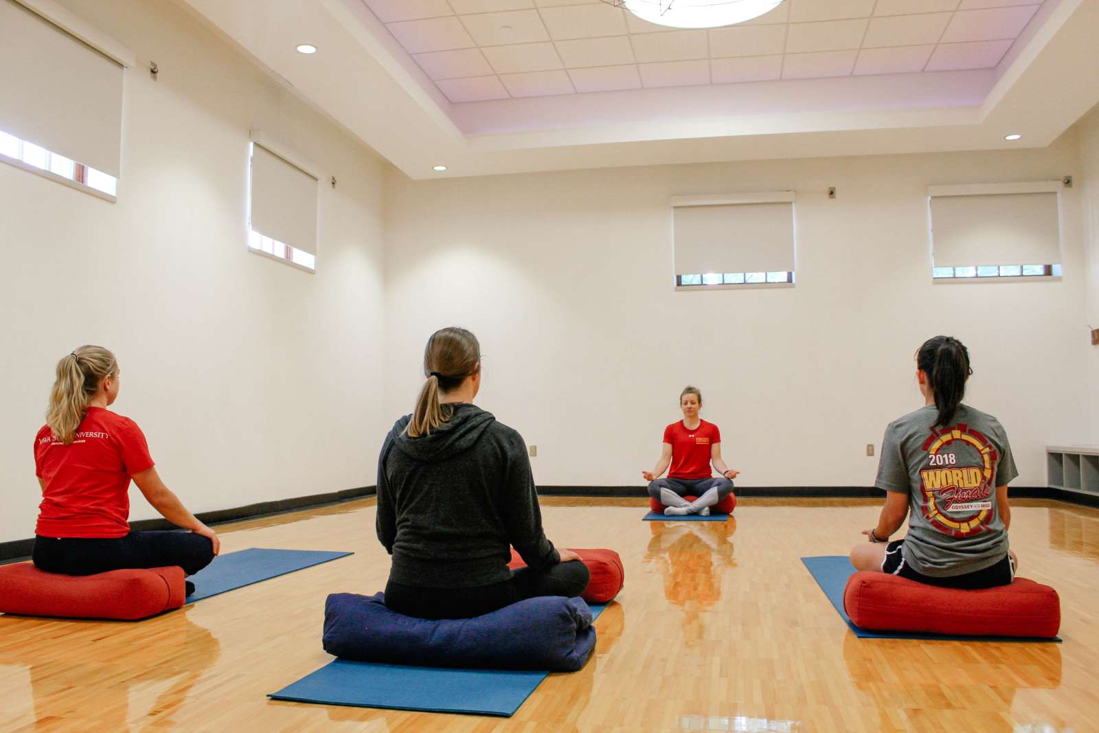 Three participants and one instructor practice relaxation techniques